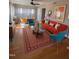 Bright living room boasts a mid-century design with an orange sofa, colorful rug, and modern artwork at 601 Aiken Pkwy, Fuquay Varina, NC 27526