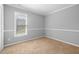 A carpeted bedroom with a large window, ample natural light, and neutral walls at 604 Chadbourne Dr, Durham, NC 27703