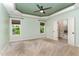 Spacious bedroom featuring a tray ceiling, ceiling fan, large windows, and access to a bathroom with tub at 70 Breadnut Dr, Smithfield, NC 27577