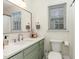 Bathroom with green vanity and marble countertop, window, round mirror and tile flooring at 7017 Sandringham Ct, Raleigh, NC 27613