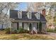 Charming home featuring dormer windows, mature trees, and a brick chimney, offering a classic and inviting curb appeal at 7017 Sandringham Ct, Raleigh, NC 27613