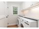 Bright laundry room features white cabinets, subway tile backsplash, marble countertop, and modern washer and dryer at 7017 Sandringham Ct, Raleigh, NC 27613