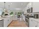 A modern, bright kitchen with white cabinetry, stainless steel appliances, and an open concept design to the dining area at 86 Olivia Crossing Ct # 3, Four Oaks, NC 27524