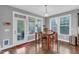 Bright dining area with a wooden table, surrounded by windows and a door to the screened porch at 156 Greenhurst Cir, Holly Springs, NC 27540