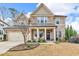 Inviting two-story home with a stone facade, manicured lawn, and a charming front porch at 156 Greenhurst Cir, Holly Springs, NC 27540