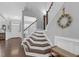 Inviting staircase with hardwood steps, a white banister, and decorative wreath detail at 156 Greenhurst Cir, Holly Springs, NC 27540