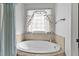 Bathroom soaking tub with tile surround, window, and sheer curtains at 180 Normandy Rd, Louisburg, NC 27549