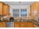 Close-up of a kitchen sink with a double window and oak cabinets at 180 Normandy Rd, Louisburg, NC 27549