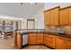 Well-lit kitchen featuring wood cabinetry, black countertops, and a view into the dining area at 180 Normandy Rd, Louisburg, NC 27549