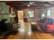 Cozy log cabin living room with hardwood floors, a wood burning stove, and comfortable seating near a window at 182 Tree Cutters, Sanford, NC 27332