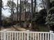 View of a backyard with mature trees, a playhouse, and a white fence at 1904 Baronsmede Dr, Raleigh, NC 27615