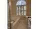 Bright bathroom featuring a soaking tub beneath a large arched window with plantation shutters at 1904 Baronsmede Dr, Raleigh, NC 27615