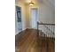 View of the hallway featuring hardwood floors, access to the bathroom, stairs, and white trim at 1904 Baronsmede Dr, Raleigh, NC 27615