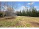 Large grassy backyard featuring a trampoline and surrounded by mature trees at 224 Swann Trl, Clayton, NC 27527