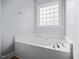 Corner view of a soaking tub with chrome faucet fixtures and a tiled privacy window above at 224 Swann Trl, Clayton, NC 27527