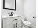 Elegant powder room with white vanity, black hardware, framed mirror, and a modern toilet at 230 Sutherland Dr, Franklinton, NC 27525