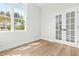 Bedroom with light walls, wood-look floors, large window, and white french doors at 230 Sutherland Dr, Franklinton, NC 27525