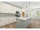 Modern kitchen featuring white cabinets, gray island, stainless appliances, and wood-look floors at 230 Sutherland Dr, Franklinton, NC 27525