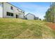 Sloping backyard leads up to the back of a home with white siding and black window trim at 240 Sutherland Dr, Franklinton, NC 27525
