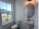 Powder room featuring a pedestal sink, oval mirror, and a window that brings in natural light at 269 Marvel Dr # 138, Rolesville, NC 27571