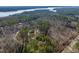 Aerial view of a beautiful home surrounded by mature trees and a beautiful lake in the distance at 38 Kingbird Ln, Chapel Hill, NC 27517