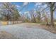 Unfenced gravel parking pad abuts the treed backyard of this property at 636 Tucker St, Burlington, NC 27215