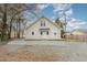 A white home with gravel parking pad has a small rear door for entry at 636 Tucker St, Burlington, NC 27215