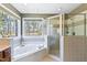 Bright bathroom featuring a corner soaking tub, walk-in shower, and serene wooded view at 6404 Pulley Town Rd, Wake Forest, NC 27587
