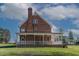 Rear view of a brick home featuring a porch and well-manicured lawn at 6404 Pulley Town Rd, Wake Forest, NC 27587