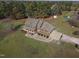 Aerial view of a brick home with a three car garage and a sprawling lawn surrounded by trees at 6404 Pulley Town Rd, Wake Forest, NC 27587