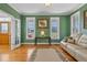 Green living room featuring hardwood floors, white sofa, french doors, and bright windows at 6404 Pulley Town Rd, Wake Forest, NC 27587