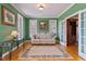 Bright living room featuring hardwood floors, white sofa, french doors, and soft green walls at 6404 Pulley Town Rd, Wake Forest, NC 27587