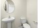 Well-lit powder room with a pedestal sink and a round mirror at 871 Forth Ct, Gibsonville, NC 27249