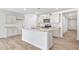 Bright kitchen features an island with granite counters, stainless appliances, and light wood-look floors at 880 Forth Ct, Gibsonville, NC 27249
