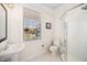 Bright bathroom featuring a walk-in shower, pedestal sink, and natural light from the window at 9344 Palm Bay Cir, Raleigh, NC 27617