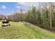 A grassy backyard featuring fire pit, sandbox and woods beyond at 1033 Leatherstone Ln, Fuquay Varina, NC 27526