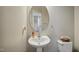 Compact powder room featuring pedestal sink and commode with decorative round mirror at 1033 Leatherstone Ln, Fuquay Varina, NC 27526