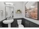 Elegant powder room with pedestal sink, black wainscoting, decorative mirror and stylish lighting at 1035 Zelkova Ln, Chapel Hill, NC 27517