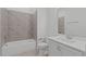 Well-lit bathroom featuring stylish gray tile, a shower-tub combo, modern fixtures, and a white vanity at 116 Pointe Park Cir, Holly Springs, NC 27540