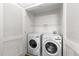 Functional laundry room with two white washing machines, storage shelf, and bi-fold door at 222 Glenwood Ave # 608, Raleigh, NC 27603