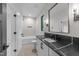 Modern bathroom features a black countertop, white cabinets and trim, and pebble tile flooring at 2305 Turners Aly, Raleigh, NC 27607