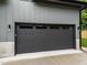 Sleek black garage door with a row of square windows is surrounded by gray siding at 2305 Turners Aly, Raleigh, NC 27607