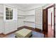 Bright walk-in closet with a window, built-in shelves and drawers, plus an ottoman on plush rug and hardwood flooring at 2421 Acanthus Dr, Wake Forest, NC 27587