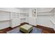 Spacious walk-in closet featuring built-in shelves and drawers, a window, plus an ottoman on plush rug and hardwood flooring at 2421 Acanthus Dr, Wake Forest, NC 27587