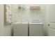 Bright laundry room with white washer and dryer, open shelving, and decorative accessories at 244 St Andrews Dr, Zebulon, NC 27597