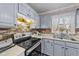 A traditionally styled kitchen features gray cabinets, stainless steel appliances, and a mosaic backsplash at 300 Pate St, Apex, NC 27502