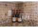 Close-up of granite countertop with tiled backsplash, wine bottles, and glasses at 3109 Doe Hill Ct, Raleigh, NC 27612