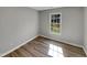 This bedroom features wood-look floors, light grey paint, a bright window, and white trim at 4804 Red Coat Ct, Raleigh, NC 27616