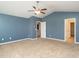 Spacious bedroom with blue walls, neutral carpet, ceiling fan and doorways at 516 Spaulding St, Burlington, NC 27215