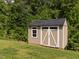 Tan shed with white trim and black roof in a grassy area surrounded by trees at 516 Spaulding St, Burlington, NC 27215
